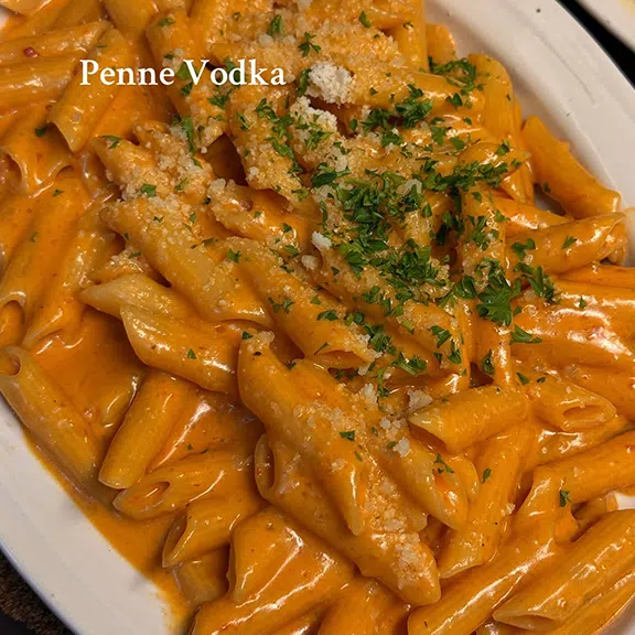 Creamy penne vodka pasta topped with herbs