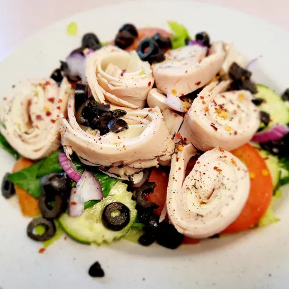 Mediterranean salad with rolled chicken, olives and fresh vegetables